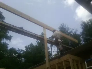 Carpenter setting a ridge beam over a new addition frame — Ice Dam Removal by Roofing Brothers in Saint Cloud
