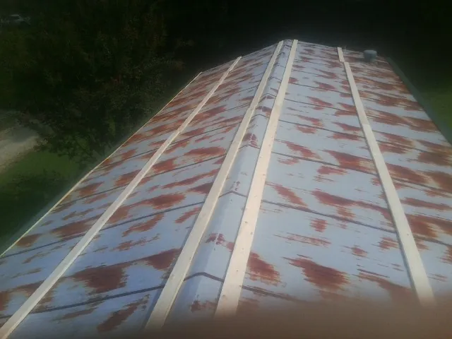 Rusted metal roof panels with new wood purlins before replacement — Storm Damage Roof Repair in Saint Cloud by Roofing Brothers