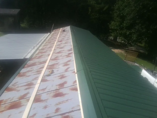 Old rusted panels beside newly installed green metal roofing — Wind Damage Roof Repair by Roofing Brothers in Saint Cloud