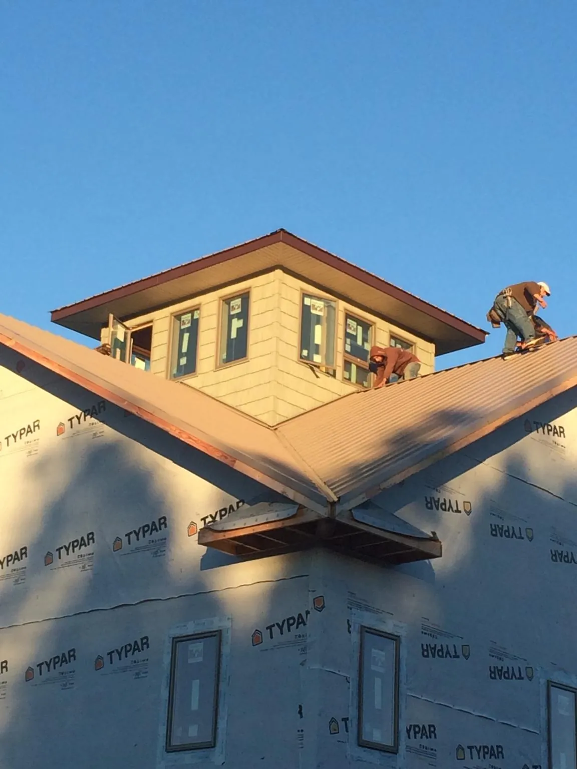 Roofers working around a rooftop cupola on a new metal roof at sunset — Roof Waterproofing in Saint Cloud by Roofing Brothers